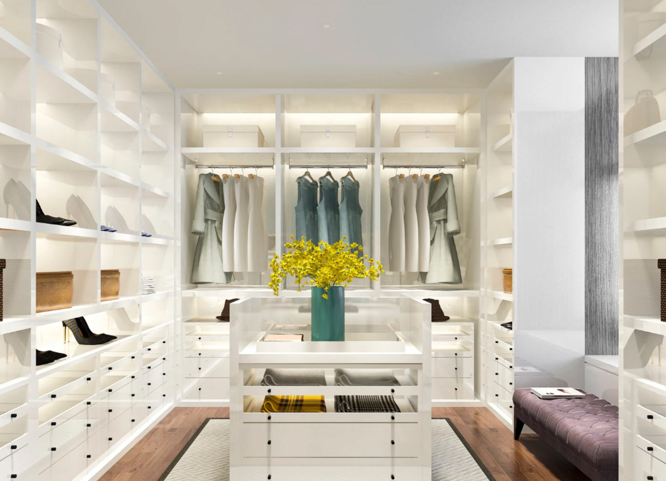 Spacious walk-in closet with white shelves, clothes, shoes, and a vase of yellow flowers on a central island.